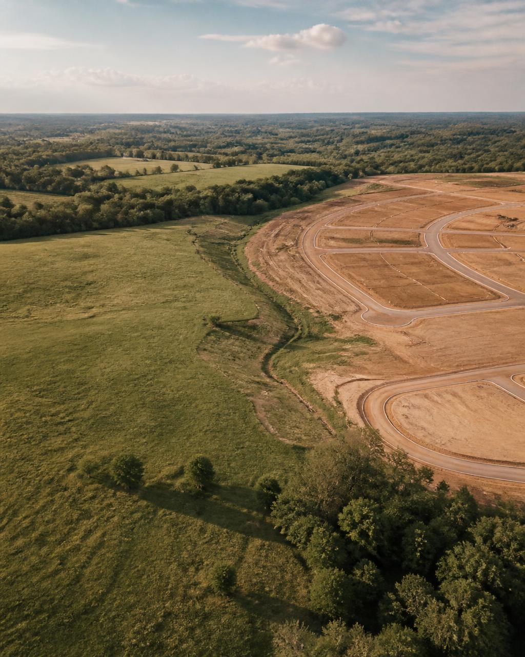 Aerial view of raw greenfield land transitioning into a planned residential development